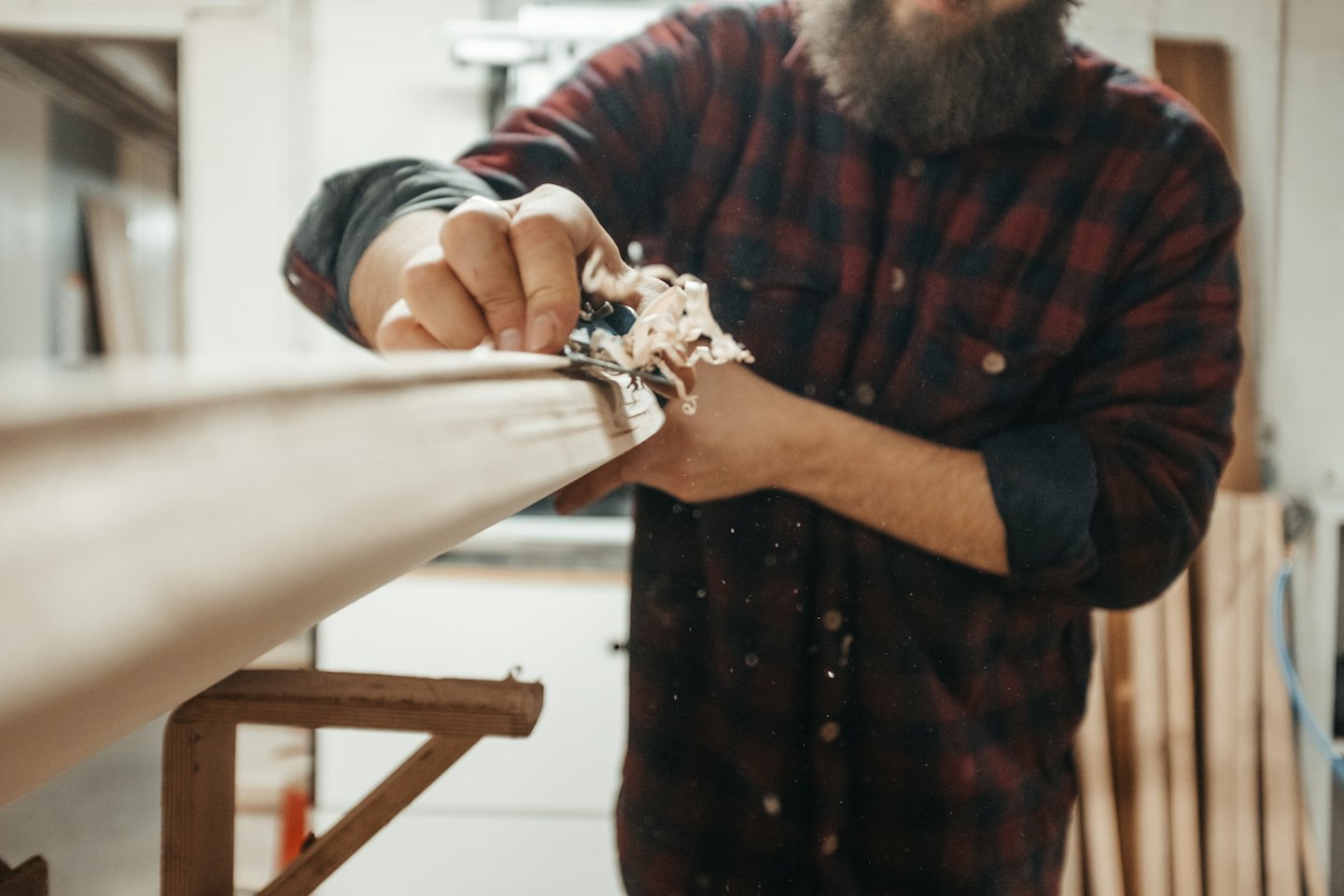 Ein Zimmermann hobelt ein Holzbrett mit einem Handhobel.
